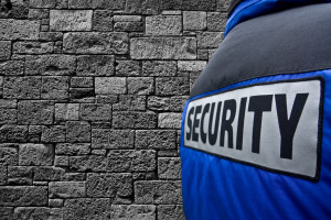 rear view at security guard next to grey wall